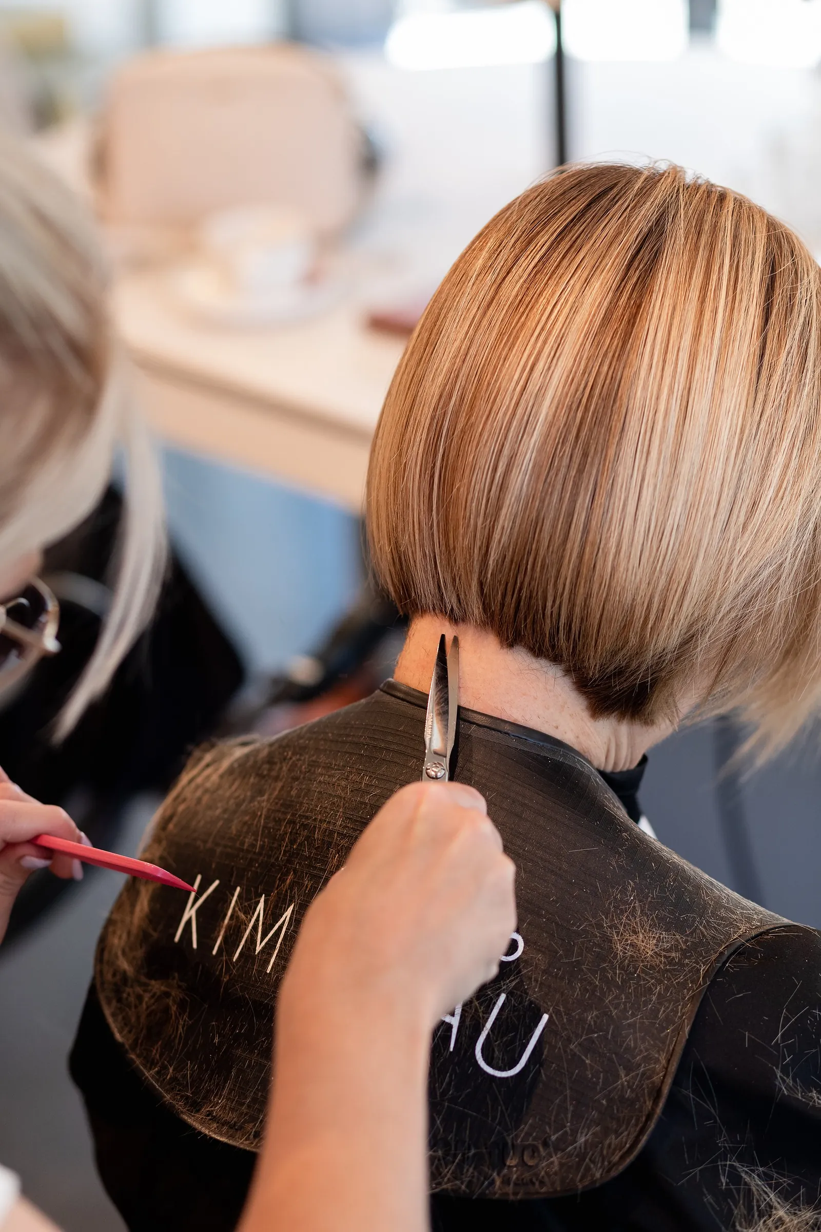 Een stylist knipt een strakke bob in het salon